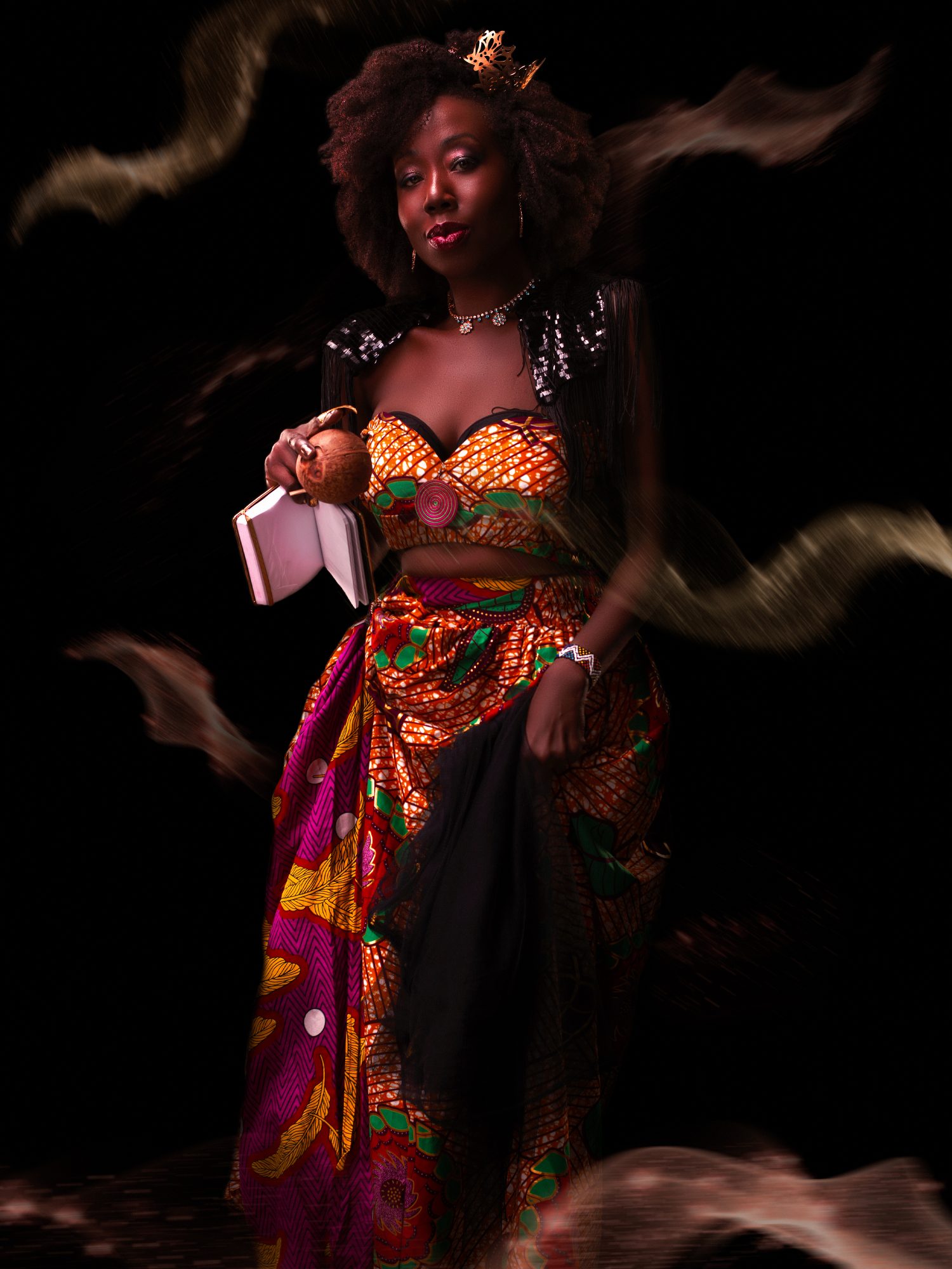 Radikal Queen Full Length, Holding a Gold Book, Ankara Skirt and Crop Top, Black Backdrop with Gold Cumulus Cloud Effect
